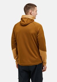 Felpa marrone con un design aderente, caratterizzata da un colletto e maniche beige a contrasto. Texture del tessuto morbida, look minimalista, senza motivi visibili.