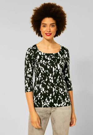 Top a fantasia in bianco e nero con scollatura rotonda, maniche tre quarti e silhouette aderente. Il materiale sembra morbido e elasticizzato.