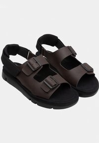 Brown leather sandals with two adjustable buckle straps, a soft textured footbed, and a sturdy black rubber outsole.