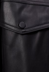 Svart läderficka med lock och täckt tryckknapp, detaljerad sömnad längs kanterna, slät textur med subtil korn.