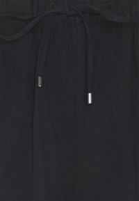 Pantalones navy hechos de una tela ligera con una cintura elástica y cordón ajustable, con puntas metálicas en los lazos y una textura suave.