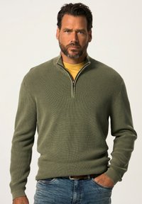 Olijfgroene half-zip sweater met een textuurgebreide ontwerp, gedragen over een gele blouse. Heeft lange mouwen en een getailleerde pasvorm.