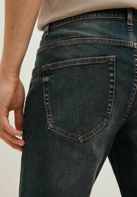 Mørke denim jeans med en let slidt tekstur, prydet med en baglomme med kontrastfarvet syning og et tæt blik på livlinjen.