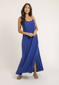 Robe maxi bleu royal avec des bretelles spaghetti, dotée d'une fente latérale et d'une coupe décontractée. Texture lisse et tissu léger.