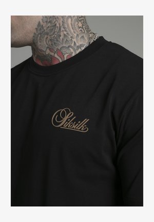Zwarte katoenen t-shirt met een ronde halslijn, met een beige geschrift logo aan de linkerkant van de borst. Gladde textuur.