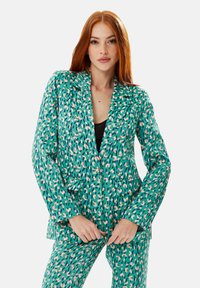 Green patterned blazer with abstract spots in pink and blue tones. Features a notched lapel and front pockets, made from lightweight fabric.