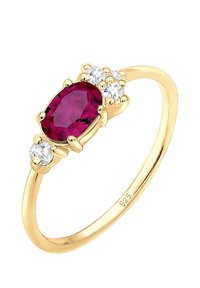 Anillo chapado en oro con una piedra central de rubí ovalada, flanqueada por tres circonitas transparentes. Banda lisa y pulida, marcada con 925.