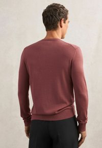 Bordowy sweter z dzianiny z długim rękawem, wykończony ściągaczami na mankietach i dole. Gładka faktura, okrągły dekolt oraz gładkie plecy.