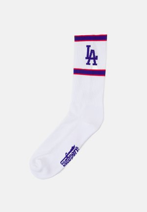 Calza sportiva bianca con strisce orizzontali rosse e blu, presenta il logo 'LA' in viola sulla parte superiore a coste e un piccolo etichetta di marca viola.
