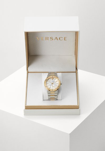 Versace hõbe- ja kuldrannekell valge puutega, metallist käevõru ning keerukate detailidega valge ja kuldse esituskastiga.