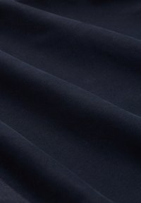 Le tissu bleu marine foncé présente une texture douce avec des plis lisses et réguliers. Le matériau semble léger et légèrement brillant sous la lumière.