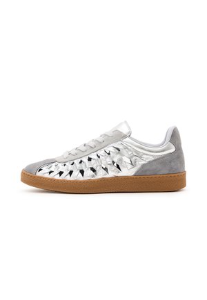Sølv sneakers med vævet metallisk overdel, grå ruskindstå og hæl, hvide snørebånd og brun gummisål, vist fra siden på hvid baggrund.