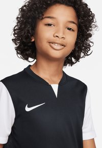 Nike-Sporttrikot mit schwarzem Körper und weißen kurzen Ärmeln, V-Ausschnitt und weißem Logo auf der Brust.