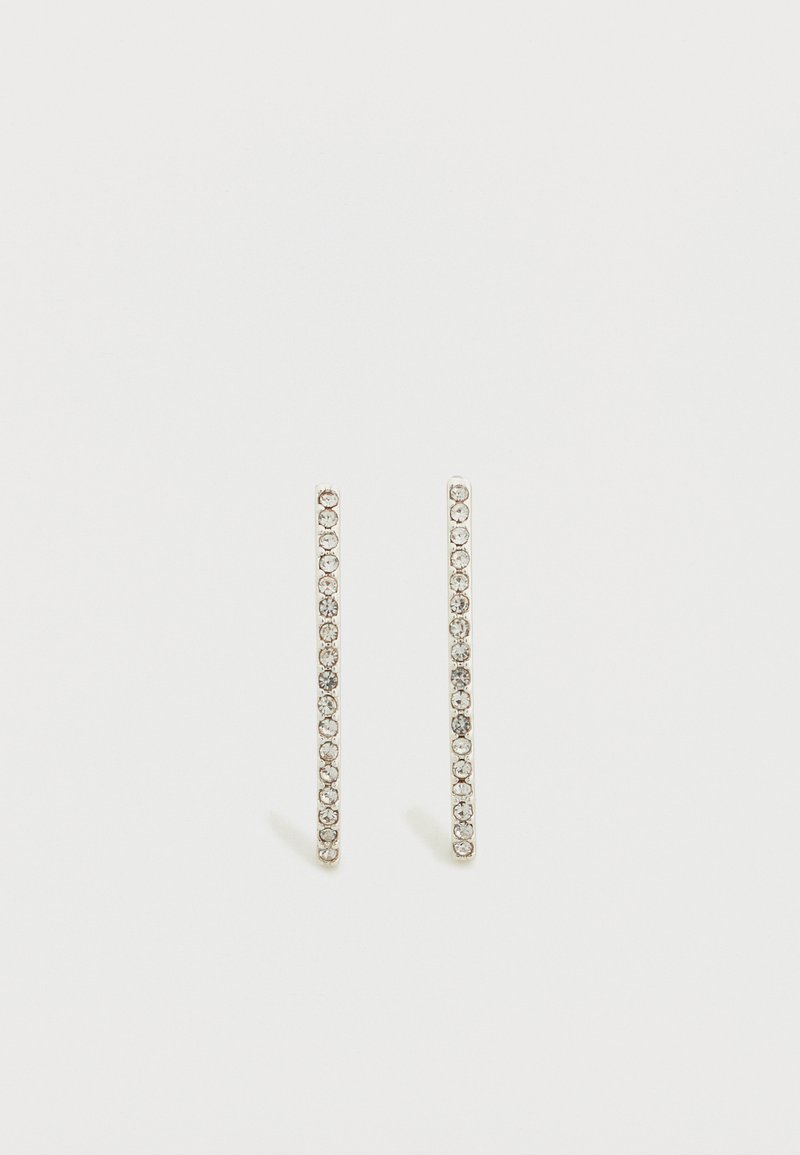 Ασημί γραμμικά σκουλαρίκια με μικρούς διαυγείς κρυστάλλους σε κατακόρυφη σειρά, που αναδεικνύουν τον κομψό και μινιμαλιστικό σχεδιασμό τους.