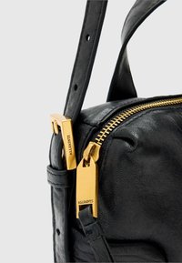 Czarna skórzana torebka na ramię z zamknięciem na zamek, wyposażona w złote okucia, regulowany pasek i teksturowane wykończenie dla dodatkowego efektu.