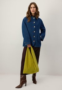 Tmavomodrá rifľová bunda so zlatými gombíkmi, skombinovaná so hnedou sukňou a hnedými špicatými čižmami. Drží veľkú zelenú mäkkú tašku.