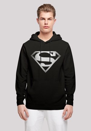 Sort hættevent med et stort, hvidt, prikket Superman-logo i en diamantform. Fremstillet af et blødt materiale med en kængurulomme.
