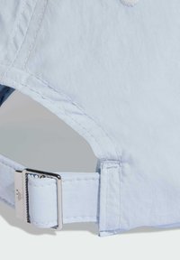 Světle modrá čepice s hladkým povrchem, vybavená stříbrnou kovovou sponou a prošívanými okraji, což svědčí o pozornosti věnované detailům v designu.