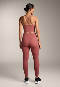 Set sportiv roz-rubin, format dintr-un bralette cu bretele și leggings cu talie înaltă, realizat dintr-un material neted și elastic, cu un design ajustat.