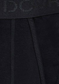 Sorte waistband med tekstureret overflade og integreret logo, ledsaget af glat, mørkt stof med synlige sømlinjer.