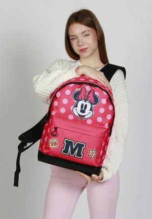 Rode en roze rugzak met stippen featuring een Minnie Mouse graphic, stoffen ritsen, "M" en ster patches, zwarte onderkant en verstelbare schouderbanden.