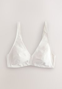 Soutien-gorge blanc à bonnets souples avec fines bretelles réglables et un profond décolleté en V, posé à plat sur une surface claire.