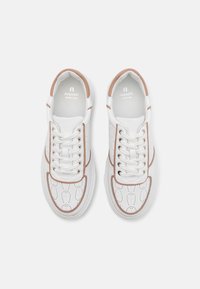 Witte sneakers met perforerend ontwerp, bruine accenten, ronde neus, platte veters en een gevoerde zool. Bevat logo binnenin de kraag.