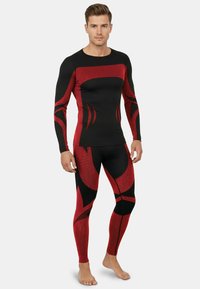 Red and black long-sleeve athletic top and leggings, featuring a ribbed texture, dynamic patterns, and a fitted design.