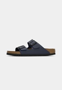 Sandales bleu marine avec deux lanières réglables, semelle en liège et semelle en caoutchouc noir. Présente des découpes latérales pour la respirabilité.