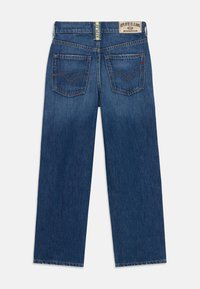 Granatowe dżinsy o szerokim kroju, tylne kieszenie z wzorem w zygzak, a zapięcie w pasie z etykietą "REPLAY BLUE JEANS."