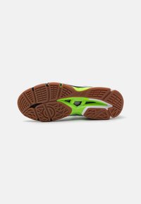 Suola delle sneaker con una base in gomma marrone, accenti verdi e un motivo testurizzato per la presa; il design include elementi di ventilazione e un battistrada pronunciato.