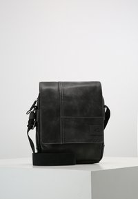 Borsa messenger in pelle nera con chiusura a pattina, tracolla regolabile e cuciture a contrasto. Include una patch con il logo per un tocco di dettaglio.