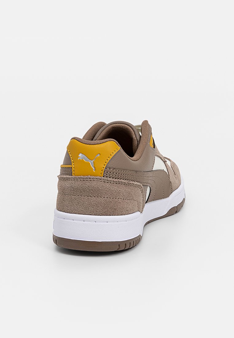 Sneaker in camoscio marrone con suola in gomma bianca, accento giallo sul tallone e dettagli del logo iconico sul retro e sul lato.