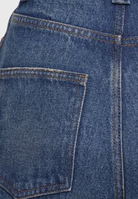 Tamsiai mėlynos džinsinės kelnės su viena užpakaline kišene. Kontrastinga oranžinė siuvinėjimo linija aplink siūles. Minkšta tekstūra su šiek tiek nusidėvėjusių išvaizda.