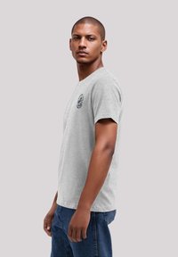 Heather grijze katoen t-shirt met een ronde hals en korte mouwen. Bevat een kleine grafische opdruk op de linkerborst en heeft een losse pasvorm.