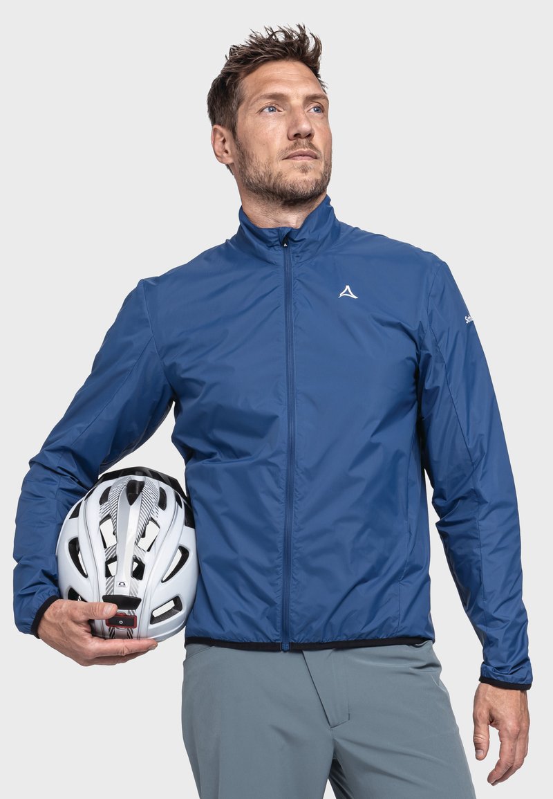 Blaues, leichtes Radtrikot mit hohem Kragen, Reißverschluss vorne und elastischem Saum. Das Modell hält einen weißen Fahrradhelm mit Lüftungsöffnungen.