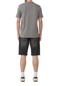 Szara koszulka krótki rękaw, luźny fason, zestawiona z ciemnoniebieskimi szortami dżinsowymi oraz białymi trampkami z czarnymi akcentami, widok z tyłu.