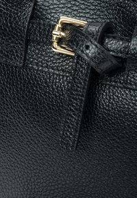 Czarna skórzana torba o fakturze z detalami w postaci złotego zapięcia i paska, z powierzchnią o strukturze przypominającej kamyk dla zwiększenia atrakcyjności wizualnej.