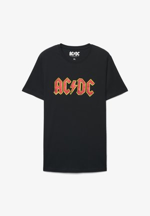 Czarny bawełniany T-shirt z dużym, wyraźnym graficznym nadrukiem AC/DC w kolorach czerwonym i żółtym, z akcentem błyskawicy na środku. Rozmiar XL.