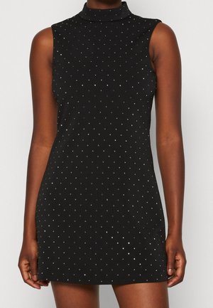 Robe courte noire sans manches avec col montant, décorée de petits clous argentés répartis de manière régulière.