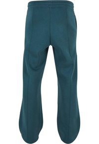 Pantalones de chándal de algodón en color verde azulado con un corte relajado, que cuentan con bolsillos laterales y detalles de costura visible. Cintura elástica para mayor comodidad.