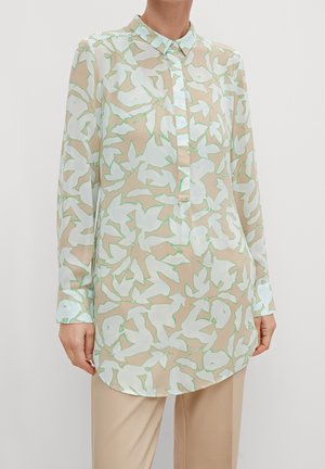 Blouse à manches longues en tissu léger et transparent. Dotée d'une base beige avec un motif floral vert pastel et blanc, col classique et fermeture à boutons.