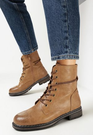 Bottes chelsea à lacets marron en faux cuir texturé avec un bout rond, une fermeture éclair latérale et des coutures blanches contrastantes sur une semelle noire.