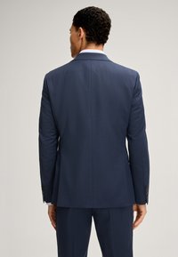 Giacca da abito blu navy con una vestibilità su misura, spalle strutturate e una texture liscia. Presenta polsini con bottoni e un'unica fessura sul retro.