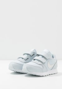 Sneakers Nike blu chiaro con tomaia in pelle liscia e rete, fasce in Velcro, punta tonda e suola in gomma bianca.