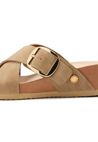 Sandalia deslizante de ante beige con un diseño de tiras cruzadas, un acento de hebilla dorada, plantilla texturizada y suela de goma. Logo de la marca visible en el costado.