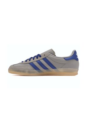 Scarpa da ginnastica Adidas grigia con strisce blu, lacci blu e suola traslucida color gomma, vista laterale su sfondo bianco.