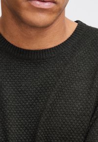 Maglione a maglia textured verde scuro con scollatura a girocollo a coste; ricorda da vicino un motivo a nido d'ape sul tessuto.