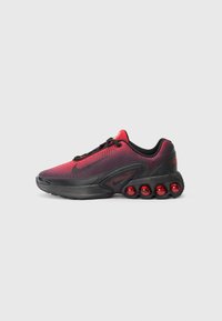 Chaussure de sport noire et rouge avec une tige en maille, un design texturé et un amorti d'air visible sous forme de sphères rouges sur la semelle.