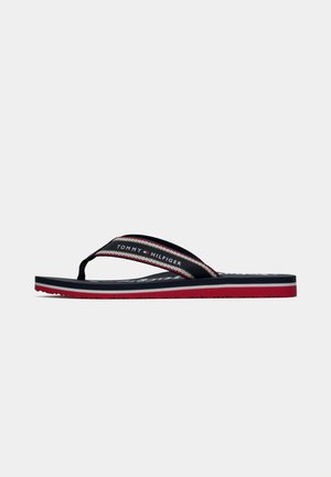 Încălțăminte flip-flop navy, roșu și alb, cu curea din țesătură în dungi, având logo-ul Tommy Hilfiger și talpă din cauciuc cu strat inferior roșu.